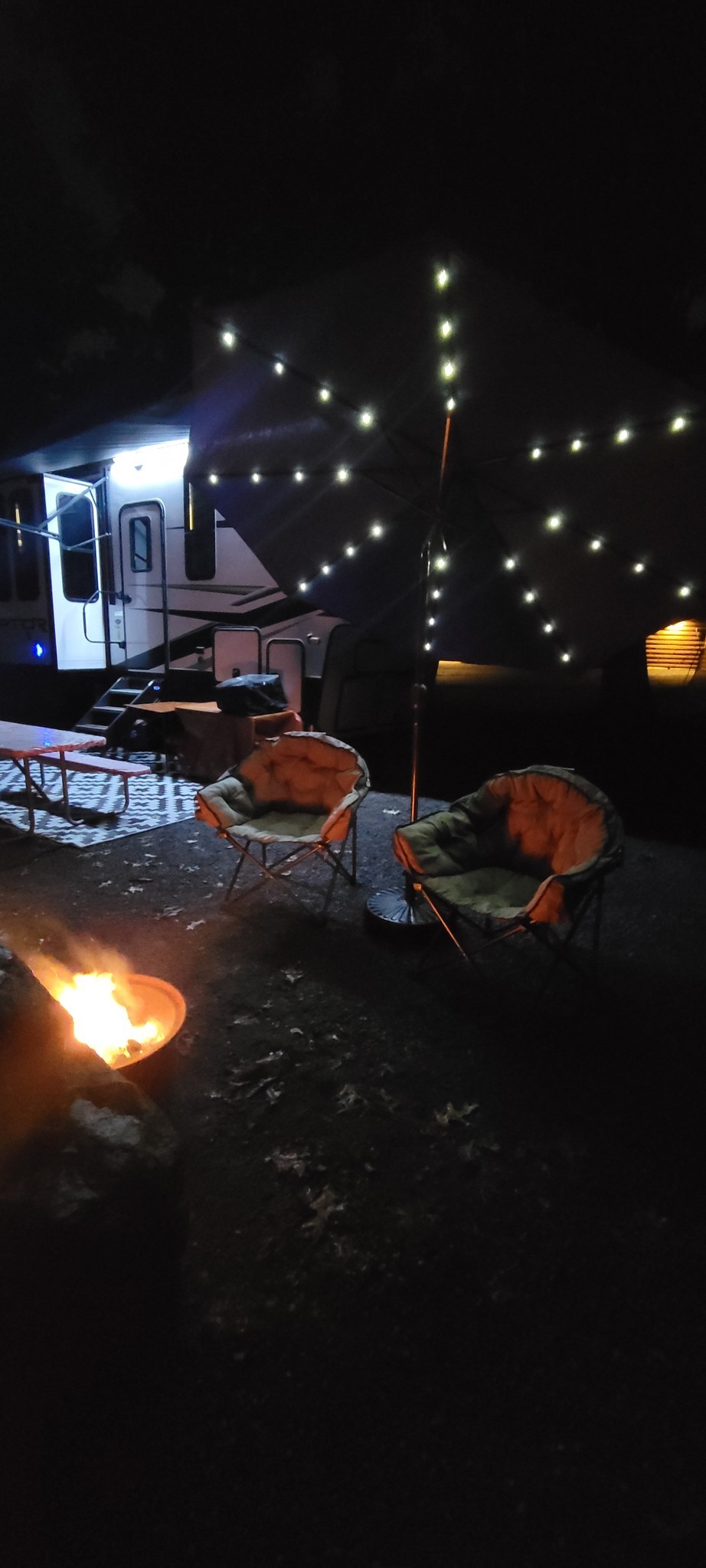 The retreat patio at night with a campfire and string lights