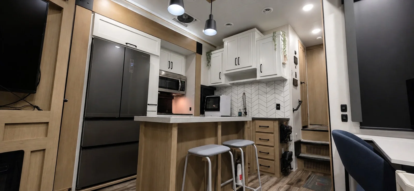 Bright full kitchen with a large refrigerator, island seating, oven, microwave, and extensive storage